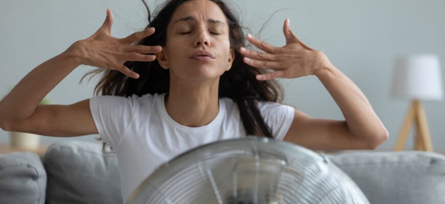 Woman,Seated,On,Couch,In,Living,Room,Suffers,From,Swelter